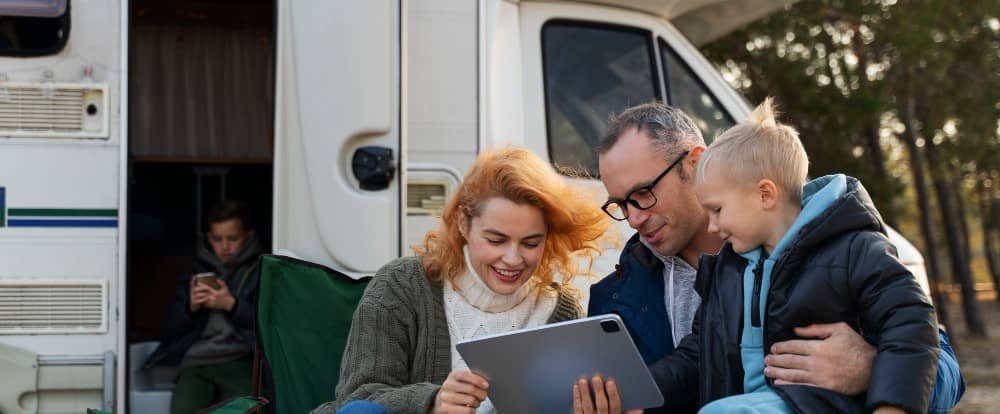 family outside rv in fall with tablet